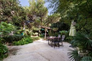 una mesa, sillas y una sombrilla en el jardín en Jardin et bambous, studio cosy, classé 2 étoiles, en Marseillan