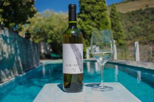 uma garrafa de vinho e um copo sentado ao lado de uma piscina em Quinta de la Rosa no Pinhão