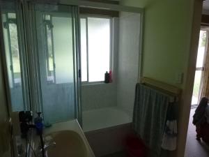 a bathroom with a shower and a tub and a sink at dad & alice's place in Tin Can Bay