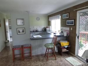 a kitchen with two stools and a counter with a sink at dad & alice's place in Tin Can Bay