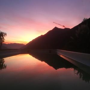 un coucher de soleil sur une étendue d'eau avec une montagne dans l'établissement Pension Apartments Klotznerhof, à Schenna