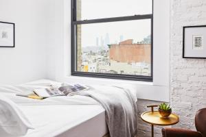 a bedroom with a bed and a large window at Walker Hotel Tribeca in New York