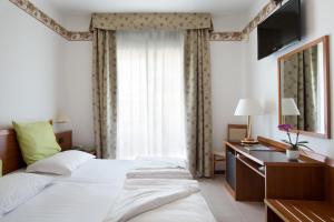 a bedroom with two beds and a desk and a window at Hotel Campagnola in Bardolino