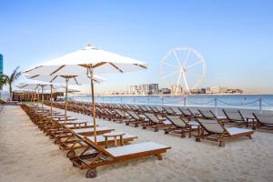 a beach area with chairs, tables and umbrellas at Sonder at JBR The Walk in Dubai