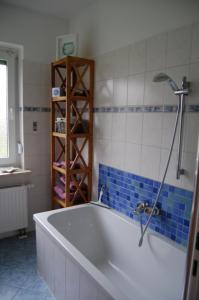 een badkamer met een bad en blauwe en witte tegels bij Harz Haus Kati - Fewo Talblick in Bad Sachsa