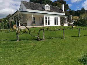 a white house with a tree in the yard at Al Der Rocs B & B in Kerikeri