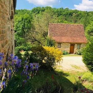 an old stone cottage with flowers in front of it at Gîte et chambres d'hôtes - Sur le chemin des sens in Azerat
