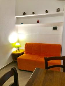 un sofá naranja en una sala de estar con mesa en Casette sul Porto, en Isquia