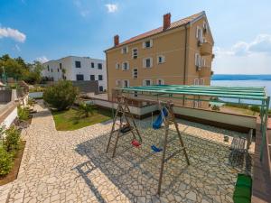 a swing set on a patio with a building at Apartments Adria in Dramalj