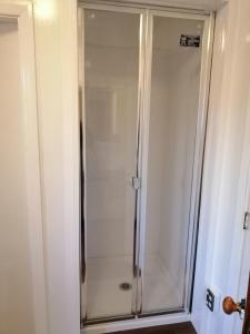 a shower with a glass door in a bathroom at Homestay Family room, near the city center in Christchurch