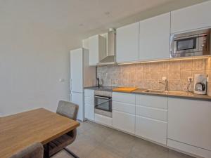 uma cozinha com armários brancos e uma mesa de madeira em House HAUS MARIJO em Crikvenica