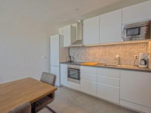 a kitchen with white cabinets and a wooden table at House HAUS MARIJO in Crikvenica +24 photos