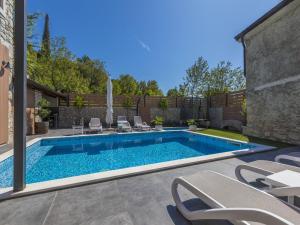 a swimming pool in a yard with chairs around it at Villa ZEN in Tribalj