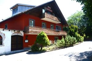 - un bâtiment rouge et blanc avec un balcon dans l'établissement Landgasthof zur Quelle, à Seeshaupt