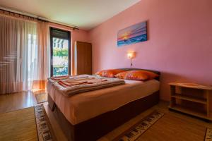 a bedroom with a bed with a pink wall at Apartments Dragica in Dramalj