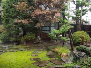 a garden with rocks and trees in front of a building at Ishiba Ryokan in Hirosaki
