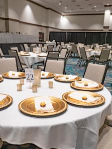 un salón de banquetes con mesas y sillas blancas en Fun City Resort Hotel, en Burlington