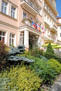 un bâtiment avec drapeaux et plantes devant lui dans l'établissement Venus, à Karlovy Vary