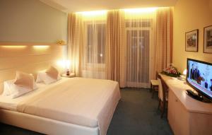 a hotel room with a bed and a desk and a television at Venus in Karlovy Vary +25 photos