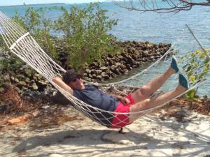 a man laying in a hammock on the beach at Hogarista Homestay in Kaledupa +22 photos