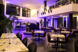 restauracja z białymi stołami i krzesłami oraz fioletowym oświetleniem w obiekcie Doulos Phos The Ship Hotel w mieście Lagoi