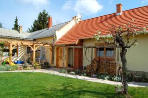 a house with a red roof and a yard at Nohab Apartman in Badacsonytördemic