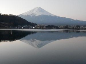 a mountain reflection in a lake with a city at Tominoko Hotel in Fujikawaguchiko