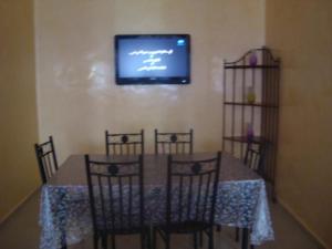 a dining room table with four chairs and a television on the wall at Apartment in Mohamadaya Morocco in Mohammedia