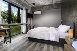 a bedroom with a bed and a desk and windows at The Nichehome Waterside Living in Chiang Mai