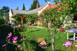 un jardín con flores, una mesa y una casa en Nohab Apartman, en Badacsonytördemic