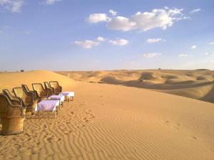 a row of tables and chairs in the desert at Sunny Desert Camp in Kūri