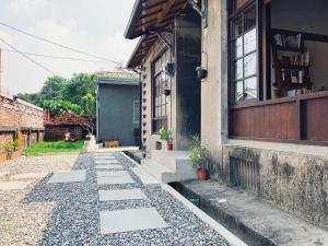 una casa con una pasarela de piedra junto a un edificio en 眷待期休憩所眷村民宿 en Kaohsiung