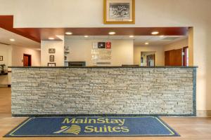 un vestíbulo con una señal de suites mainsburys frente a un mostrador de piedra en MainStay Suites Grantville en Grantville