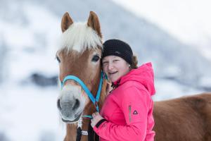 une femme en veste rose embrassant un cheval brun dans l'établissement Hieserhof, à Neustift im Stubaital