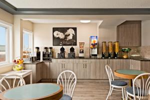 a kitchen with tables and chairs and a counter with wine bottles at Travelodge by Wyndham Calgary South in Calgary