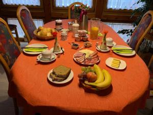 BurladingenにあるGästezimmer Schanz-Hilbelのオレンジのテーブルクロスに食べ物と果物を添えたテーブル