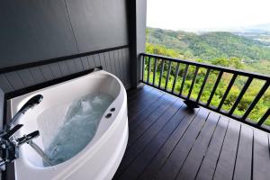 Phuket View Coffee and Resort في تشالونج: حوض استحمام في غرفة مع شرفة
