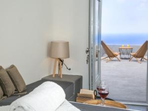 a living room with a glass of wine and a window at Santorini Villas in Vourvoúlos