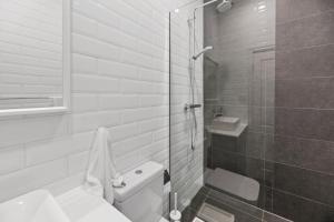 a white bathroom with a shower and a toilet at Work Sleep Live Melbourne in Melbourne
