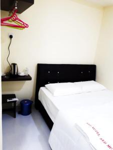 a bedroom with two white beds and a black headboard at Red Motel in Nibung Tebal