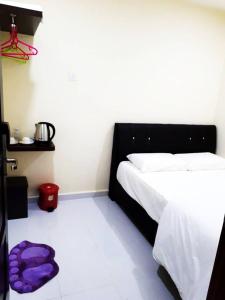 a bedroom with a bed with a purple blanket on the floor at Red Motel in Nibung Tebal