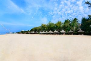 Four Oceans Beach Resort - Bon Bien Mui Ne في موي ني: شاطئ رملي عليه مظلات وكراسي