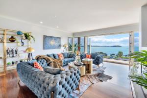 - un salon avec des canapés bleus et une grande fenêtre dans l'établissement Orakei Grandeur Mansion with Sea Views & Pool, à Auckland