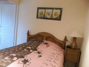 a bed with a pink comforter with flowers on it at Le Grenier in Bief-des-Maisons