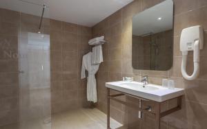 a bathroom with a sink and a mirror and a shower at Hotel Nour Congress & Resort in Bizerte