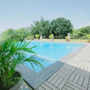 a large swimming pool with plants in a yard at Silverador Resort in Thane