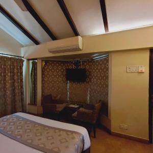 a bedroom with a bed and a desk and a television at Silverador Resort in Thane