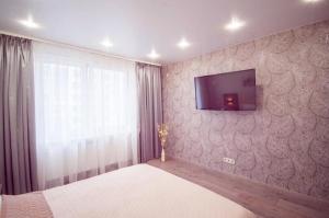 チュメニにあるAtma House однокомнатная квартира у Аквапаркаの壁にテレビ付きのベッドルーム1室