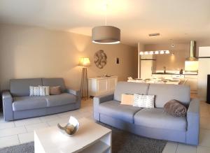 a living room with two couches and a kitchen at Résidence Le Cosimo in LʼÎle-Rousse