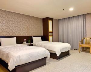 una habitación de hotel con 2 camas y una silla en Jing Dian Business Hotel, en Taoyuan